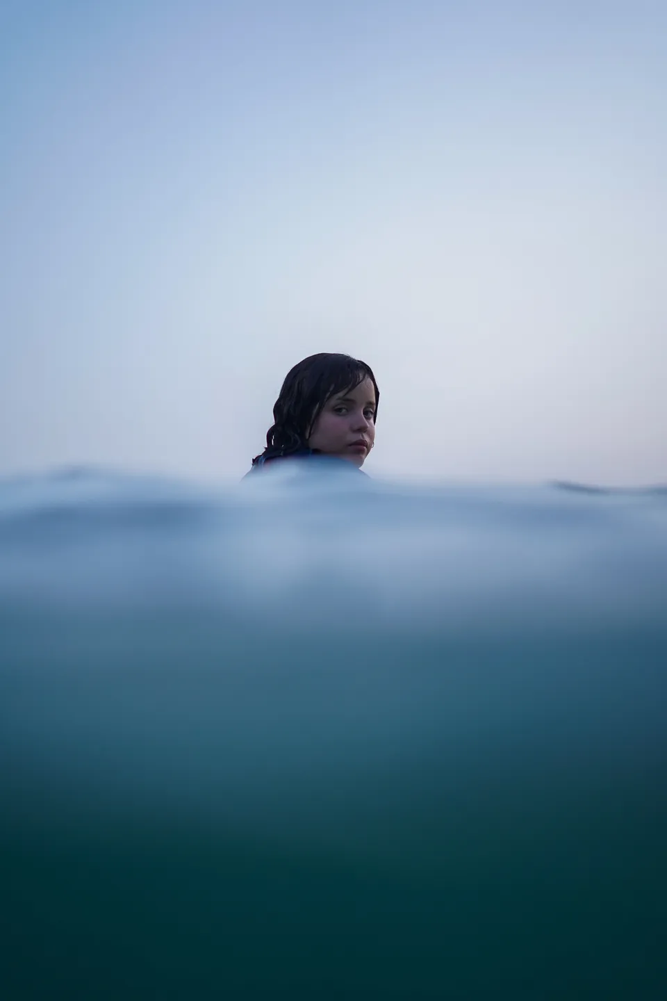 Half-underwater dome portrait of a surfer at blue hour