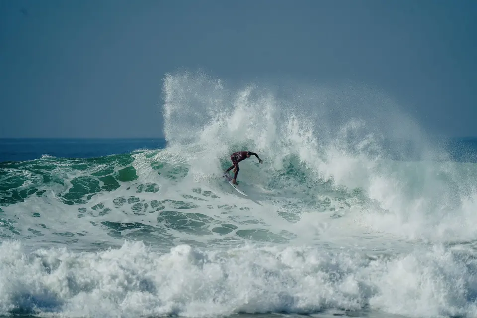 Surfer carving across a blue wave