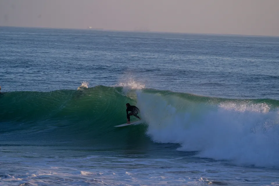 Surfer dropping into a clean green Atlantic barrel at sunrise